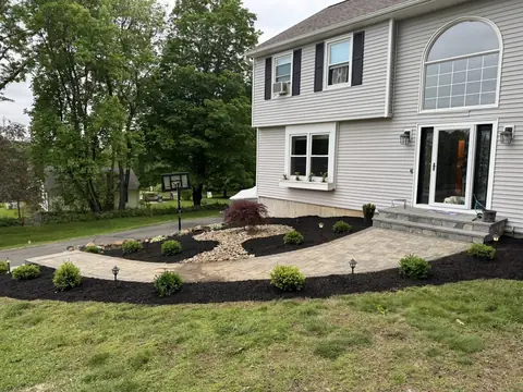 A stone walkway curving to a front door with fresh planting beds