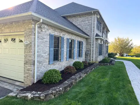 Fieldstone edging along a mulch bed beside a stone-faced house