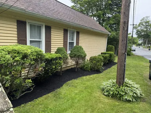 Trimmed shrubs in a fresh mulch bed along the side of a house